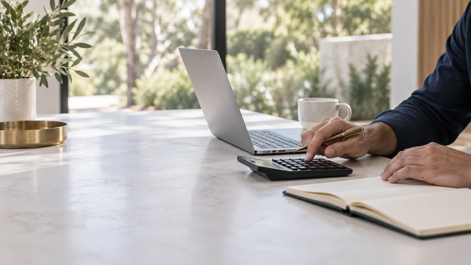 Hands using a calculator beside a notebook and laptop